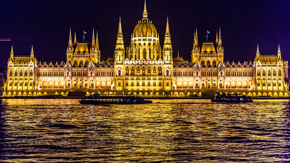 Hungarian Parliament building illuminated at night with golden lights reflecting on the Danube River