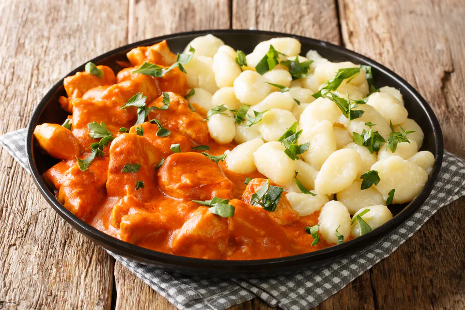 Traditional Hungarian chicken paprikash with dumplings served in rustic restaurant setting