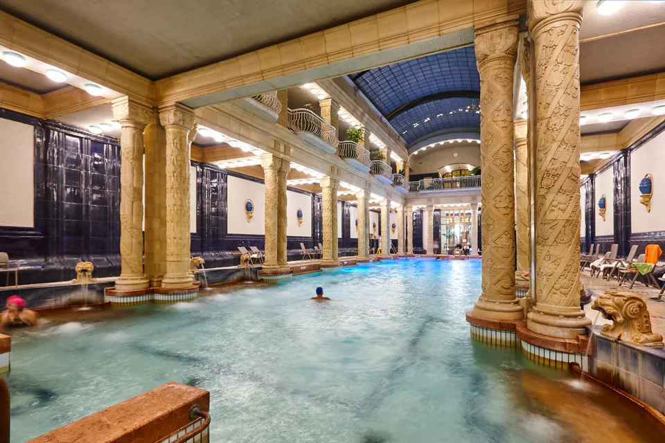 Historic indoor thermal pool surrounded by ornate Art Nouveau columns and decorative tilework