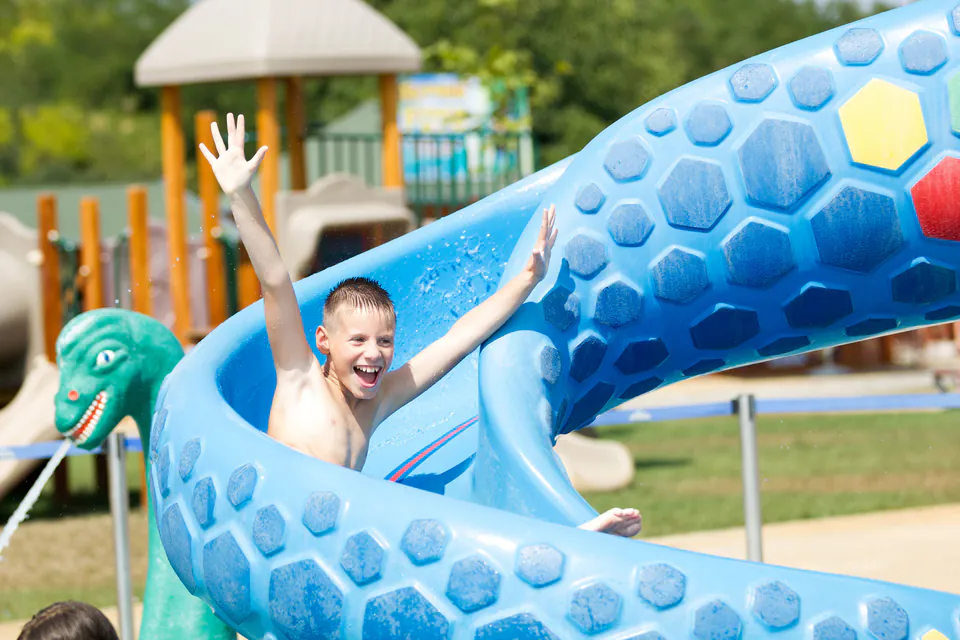 Child enjoying a blue water slide at an aquatic park