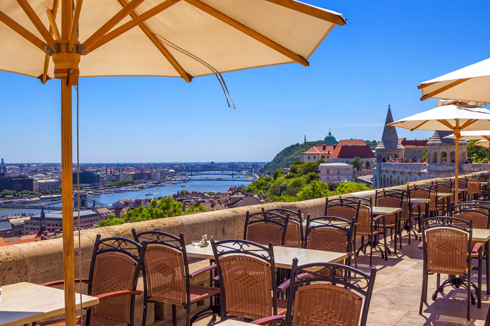 Restaurant terrace with umbrellas overlooking Budapest's Danube River and cityscape