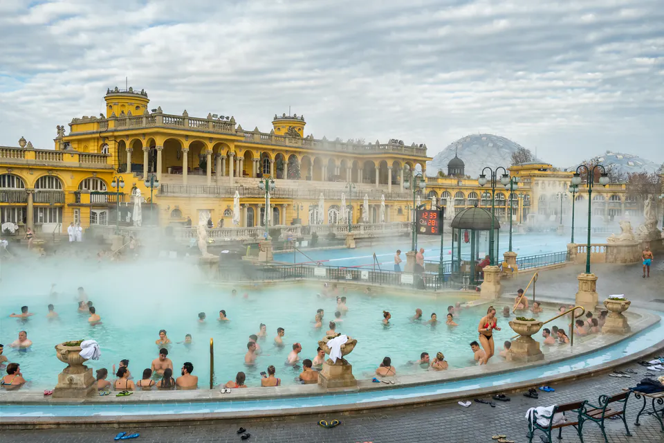Steamy outdoor thermal pool with historic yellow building in winter atmosphere