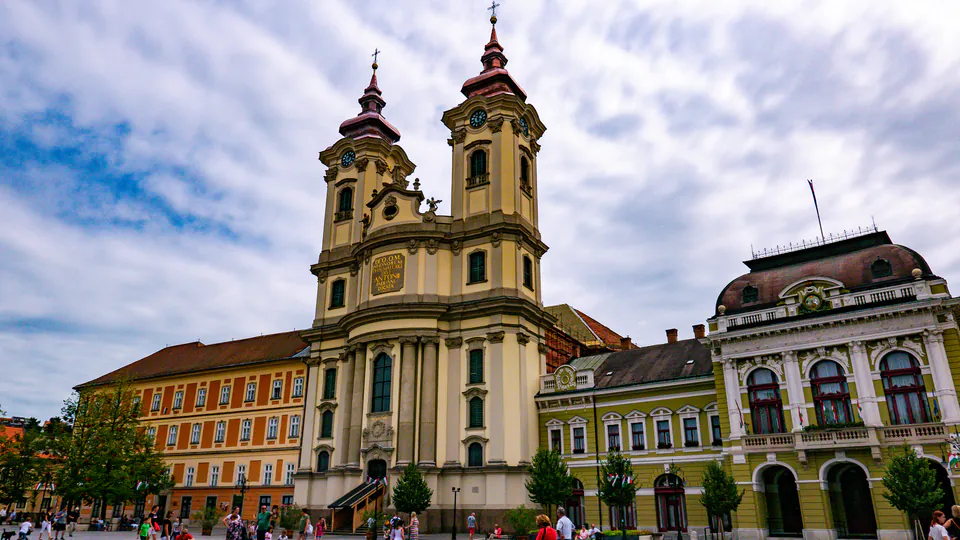 Historic church with twin baroque towers rises above colorful buildings in Eger's town center