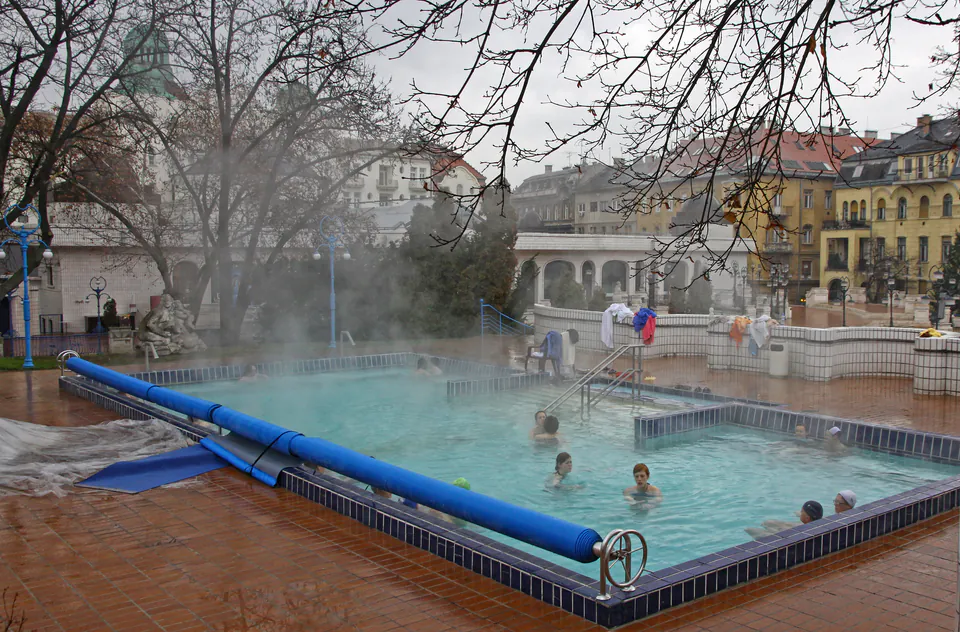 Steaming outdoor thermal pool with bathers enjoying warm waters on a cold winter day