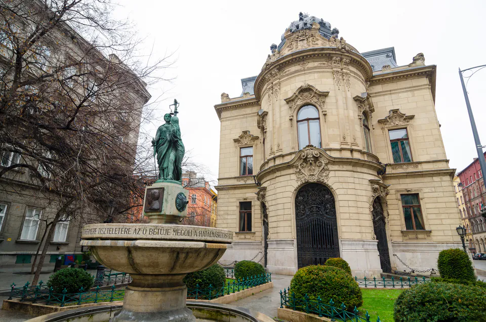 Ornate baroque palace exterior with fountain and statue in foreground