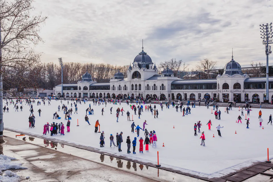 Children ice skating at City Park winter ice rink with castle in background