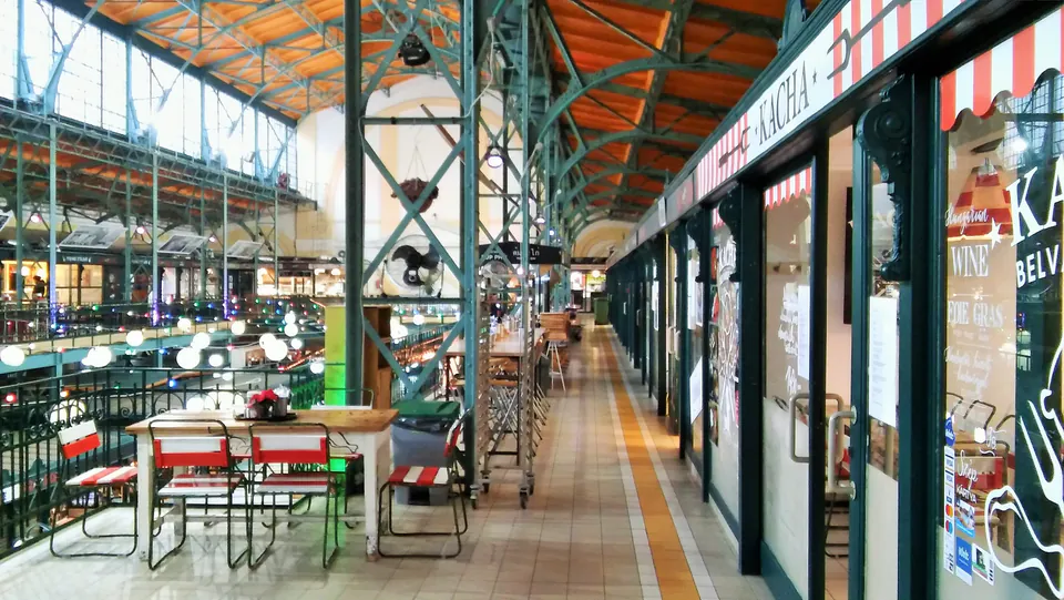 Renovated market hall corridor with modern storefronts, seating areas and preserved historic ceiling