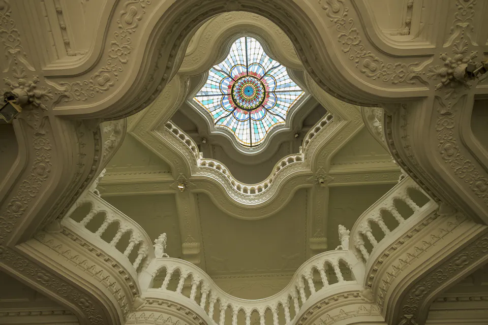 Ornate Art Nouveau ceiling with stained glass skylight and decorative white architectural details