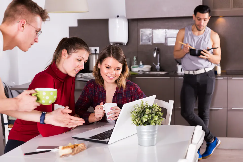 Travelers socializing in a modern hostel kitchen and common area