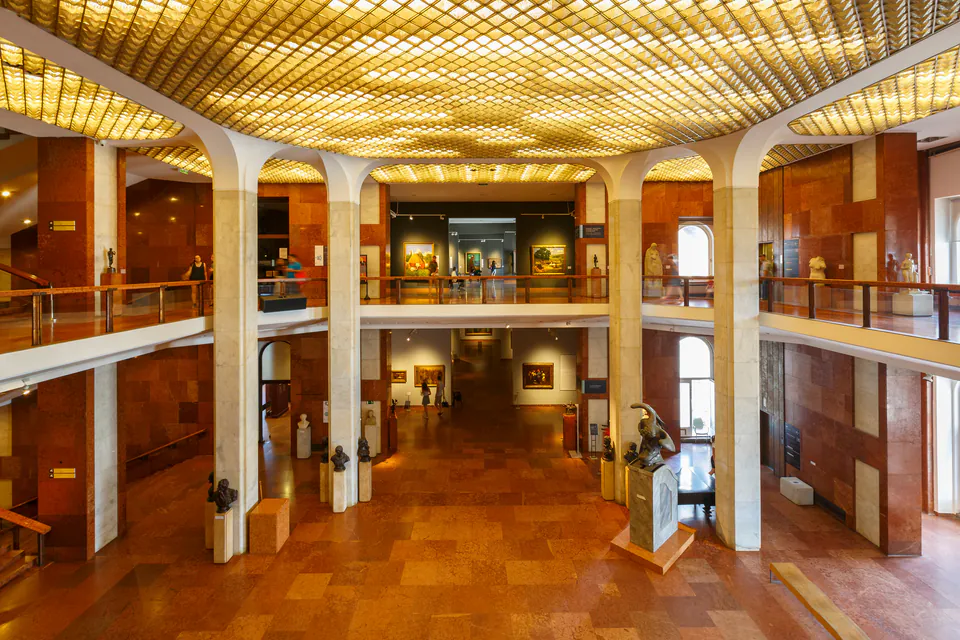 Modern gallery interior with golden ceiling grid and two-story exhibition space