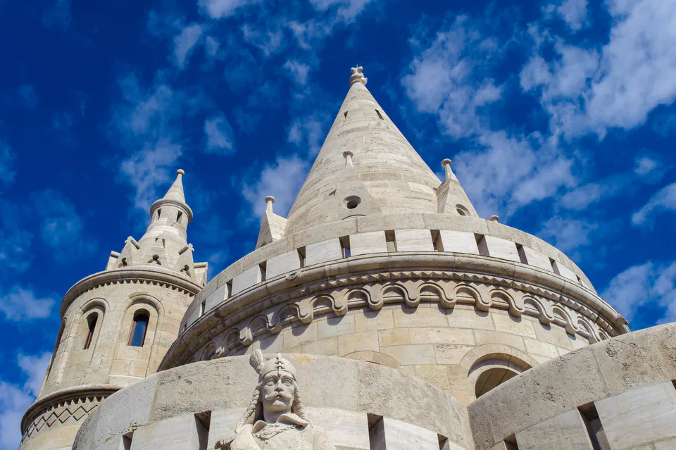 White conical towers and neo-Romanesque architectural details of Fisherman's Bastion against blue sky