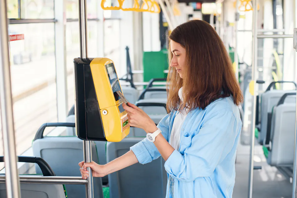 Red manual ticket validator inside Budapest tram with passenger validating ticket