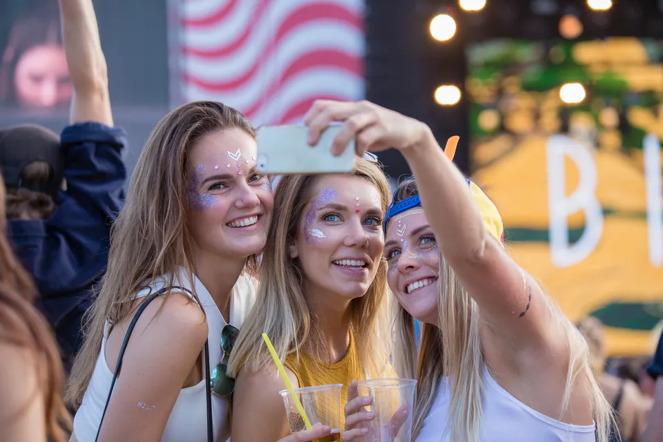 Festival attendees with colorful face paint enjoying themselves at an outdoor music event