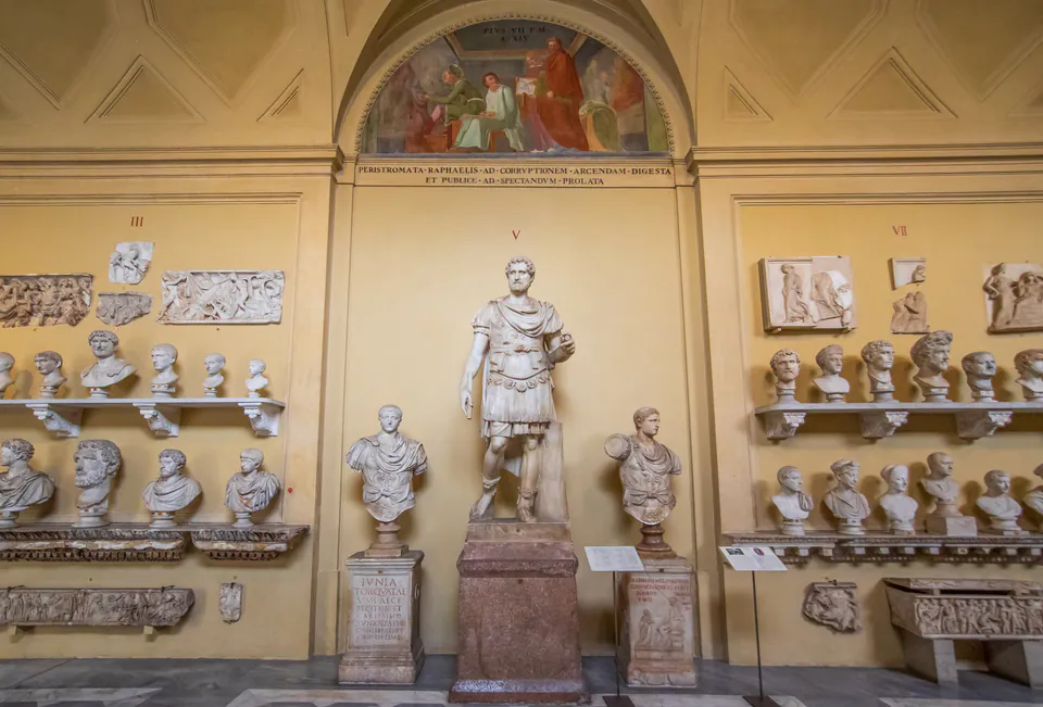 Ancient Roman stone sculptures and busts displayed on museum walls with central statue