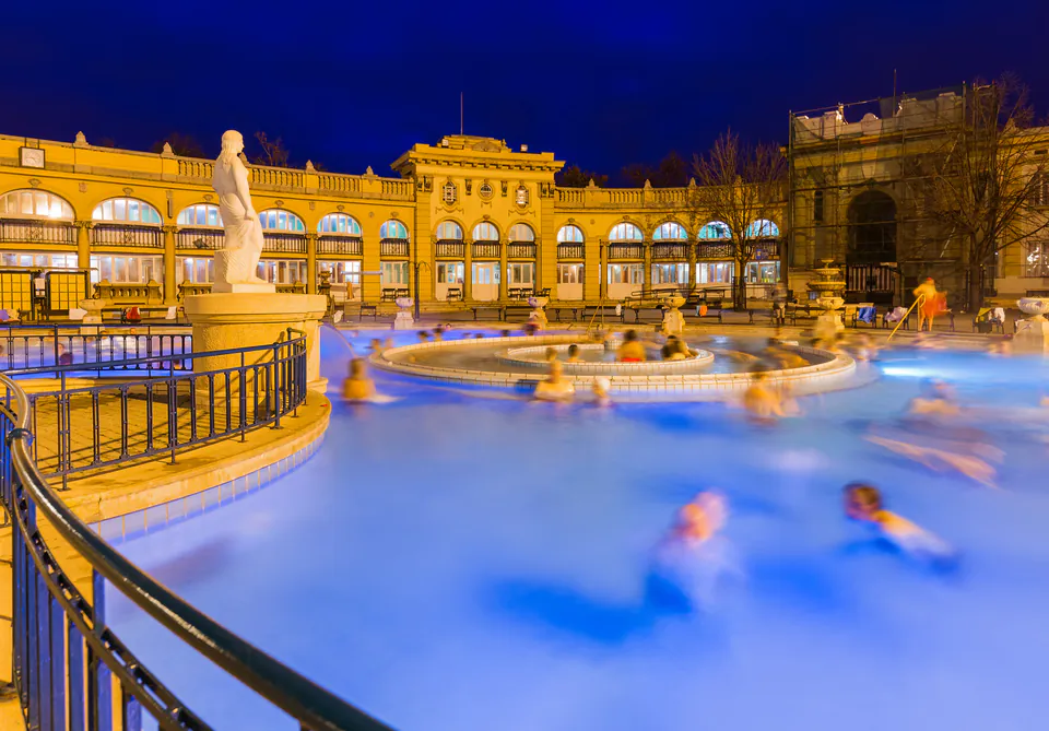 Couple relaxing in outdoor thermal pool with steam rising at sunset