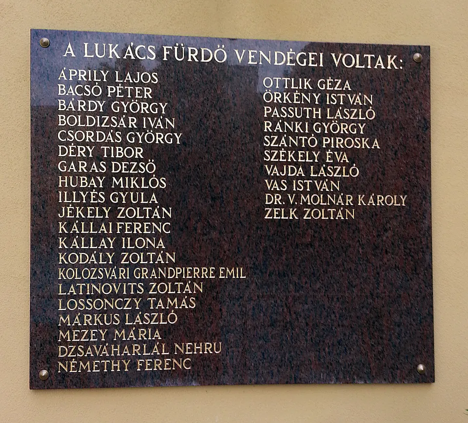 Historic marble plaque listing names of notable visitors to Lukács Bath in Hungarian text
