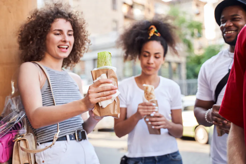 Tourists sampling street food and enjoying casual conversation during a food tour