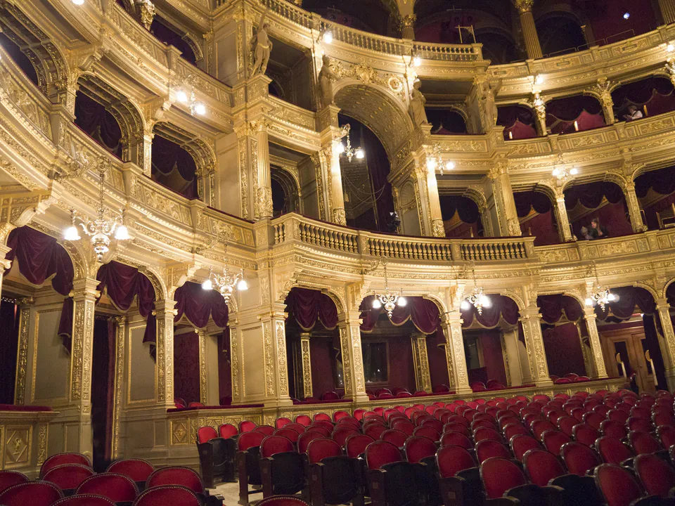 Opera house interior showing multiple levels of ornate boxes with red velvet seats and gilded details