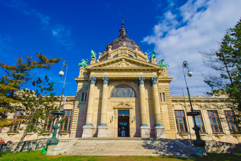 Ornate neo-baroque entrance to Széchenyi Baths with grand stone steps and domed architecture