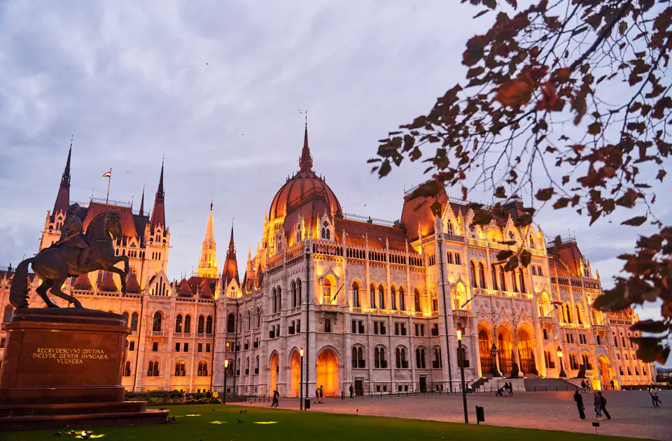 Hungarian Parliament building illuminated at sunset reflecting in the Danube