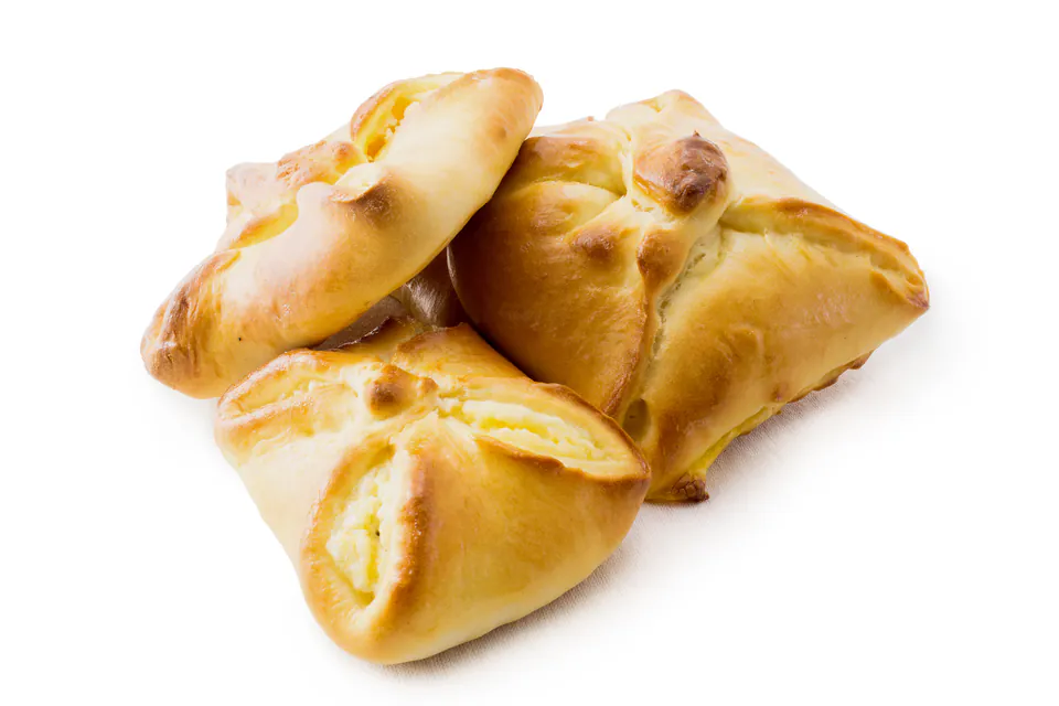 Golden-brown Hungarian pogácsa pastries with savory filling on white background