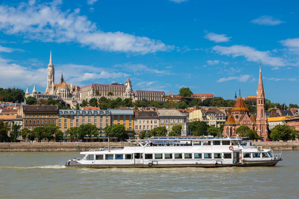 River cruise boat passing Matthias Church and Fisherman's Bastion along Budapest's Danube riverfront