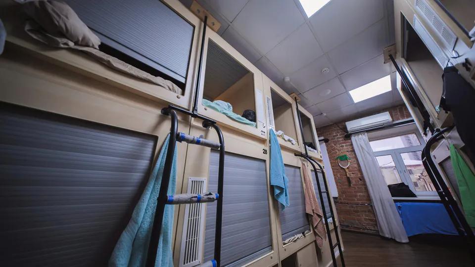 Modern hostel bunk beds with privacy curtains and built-in storage compartments
