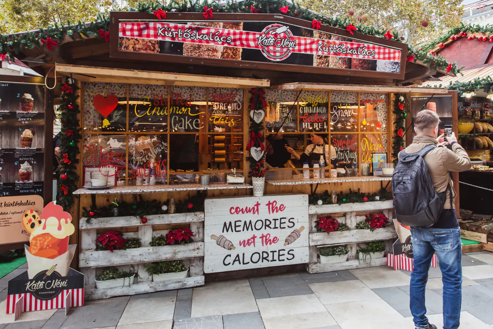 Festive kürtőskalács stand decorated with Christmas garlands and red ornaments at Budapest market