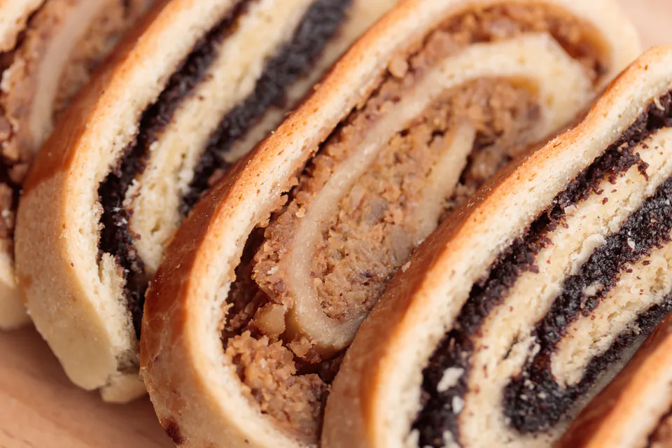 Close-up of sliced bejgli pastry roll showing swirled layers of poppy seed and walnut filling