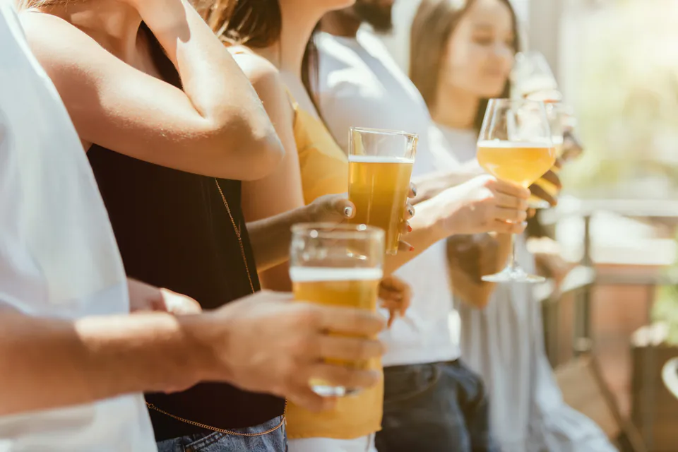 People holding glasses of craft beer at an outdoor festival setting