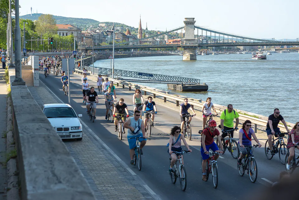 Cyclists riding along Danube riverfront with Chain Bridge and city skyline in background