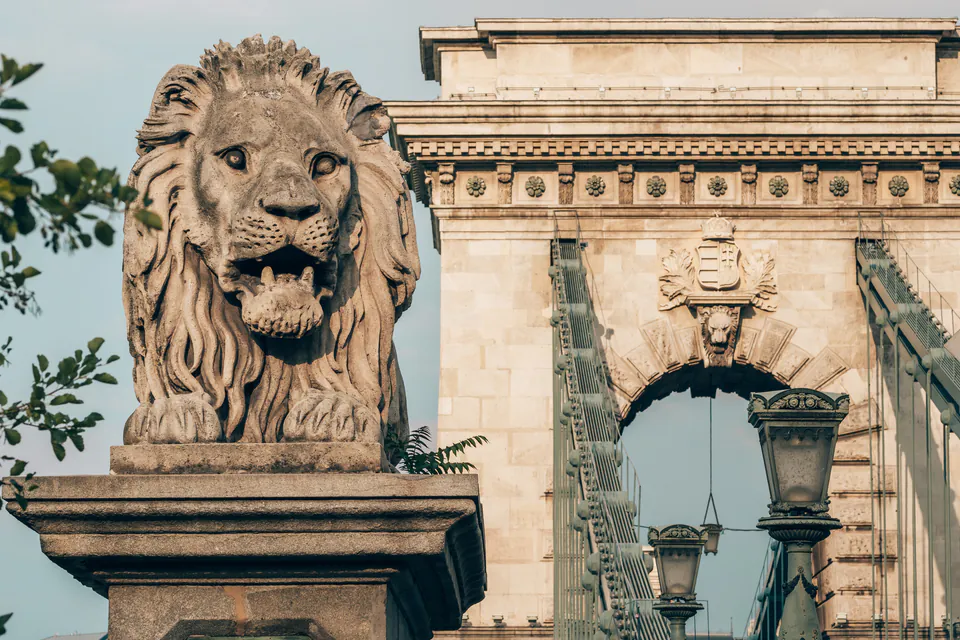Close-up of limestone lion statue head with bridge architecture visible in background
