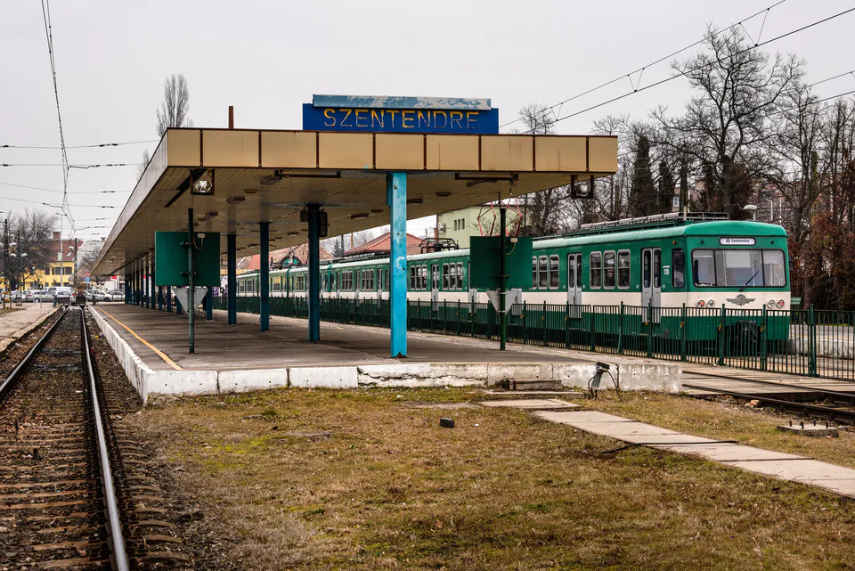 Green HÉV train stationed at Szentendre terminal platform under covered waiting area