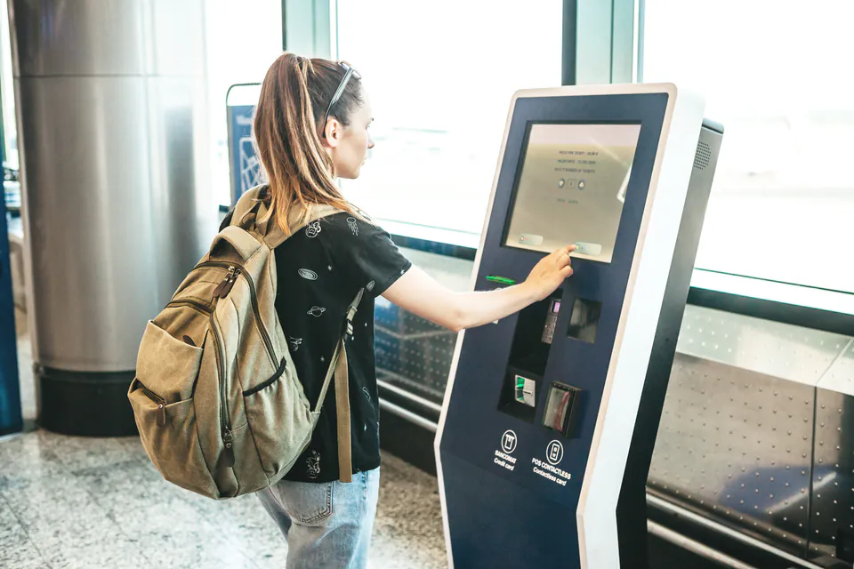 Traveler using self-service ticket machine at transportation station