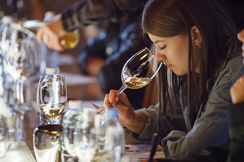 Person examining wine during a guided tasting session at a dimly lit table