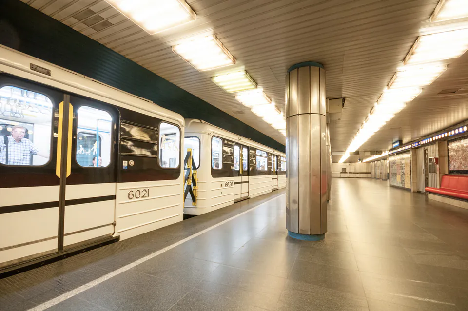 Metro train stopped at Opera station platform with white walls and fluorescent lighting