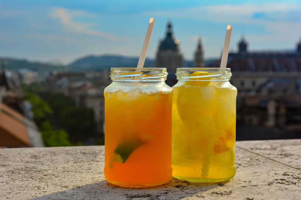 Two mason jar cocktails on rooftop ledge with Budapest skyline in background