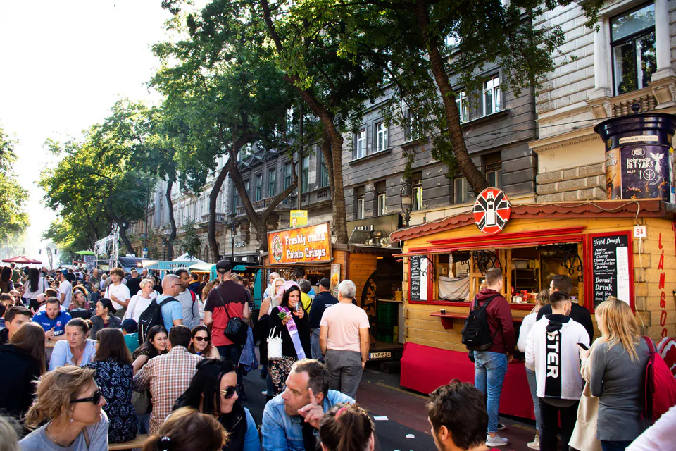 Busy street lined with food trucks and international dining options with crowds of people