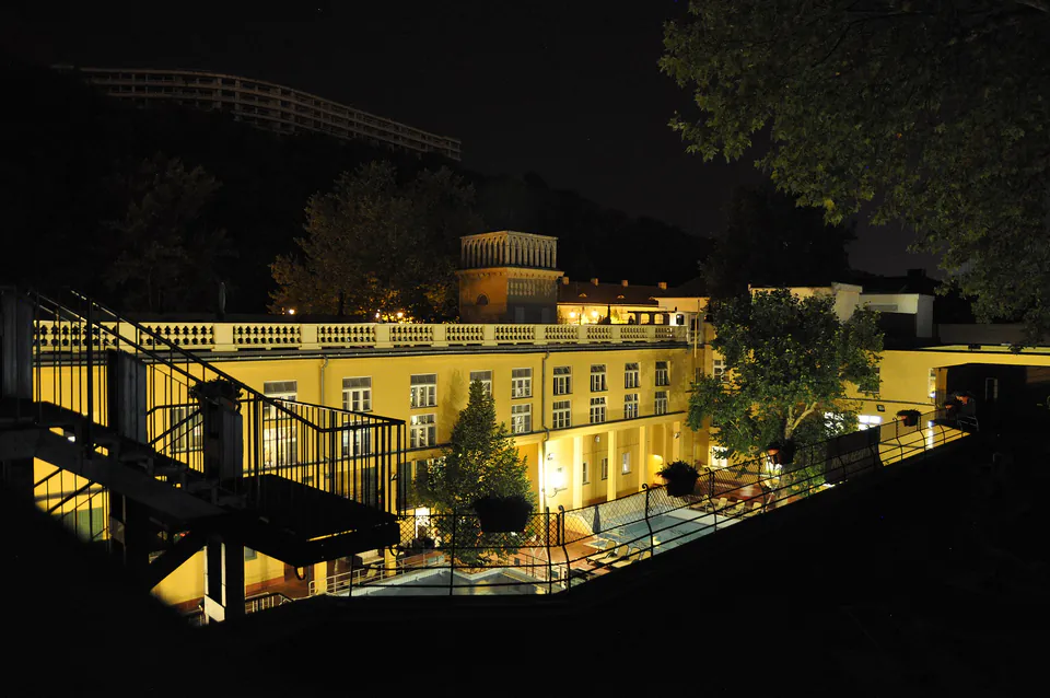 Illuminated exterior of Lukács Bath at night showing lit walkways and historic architecture