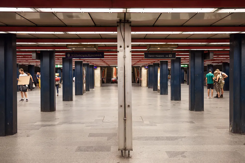 Modern metro station interior with blue pillars and red ceiling lighting