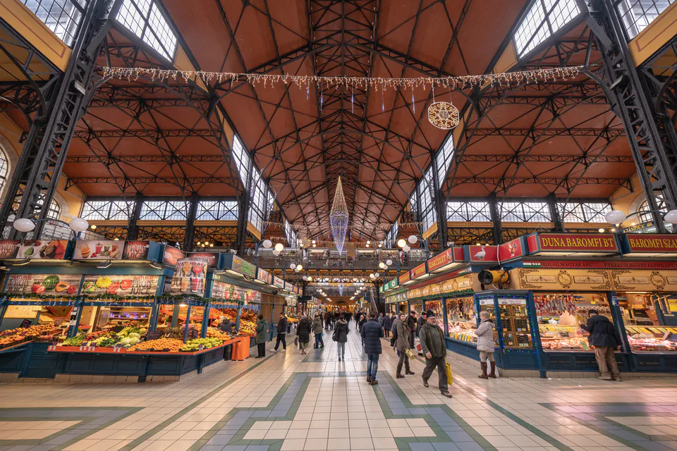 Interior view of Budapest's Great Market Hall showing food stalls, high ceiling, and shopping corridor