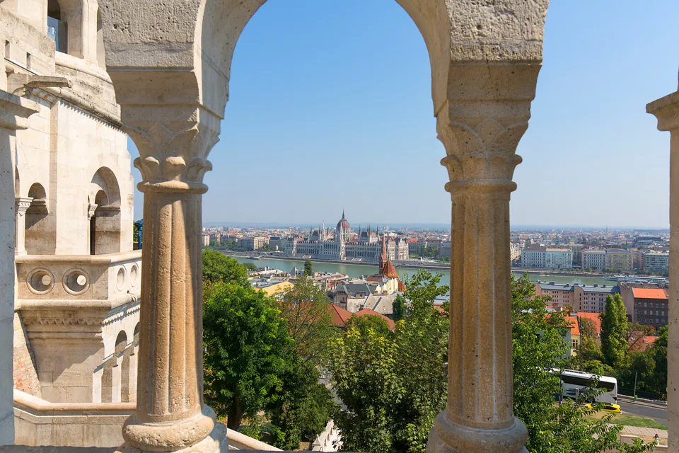 View of Parliament and Danube River through stone archways of Buda Castle terrace