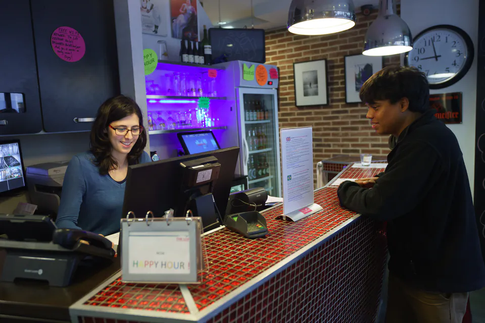 Guest checking in at a hostel reception desk with friendly staff member