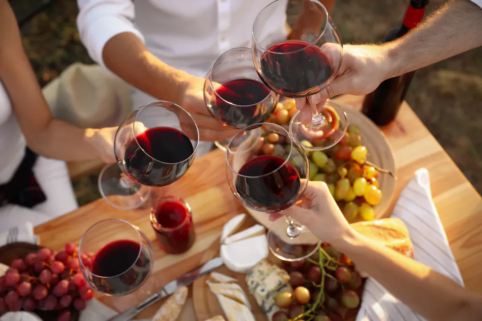 Wine glasses clinking together over a table with cheese, grapes and appetizers