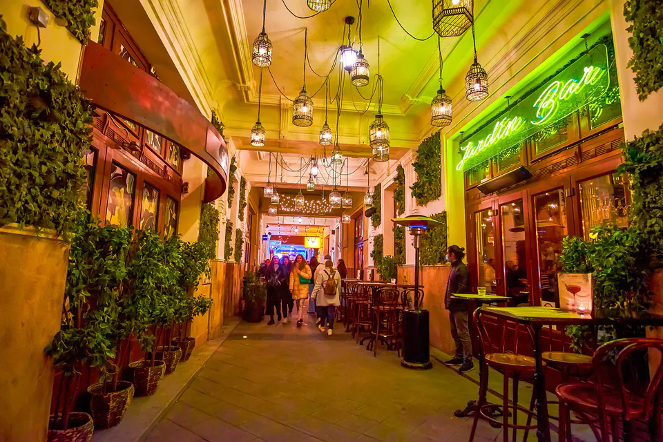 Illuminated entrance corridor of a ruin pub with hanging lanterns and neon signs