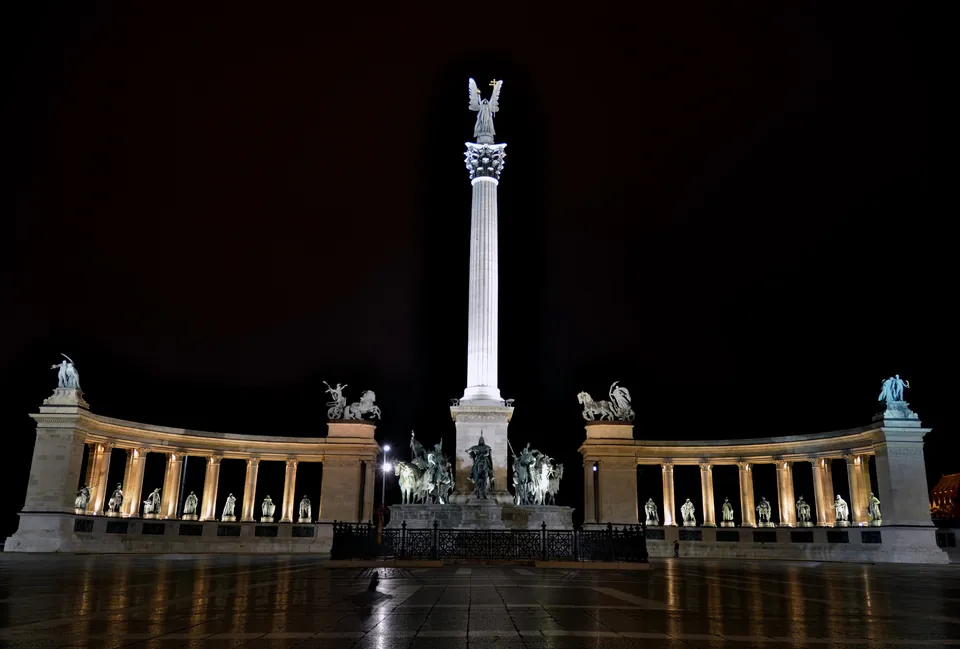 Heroes' Square monument and colonnades illuminated against dark night sky in Budapest