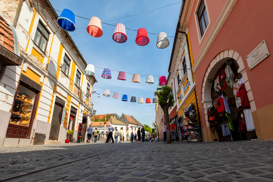 Colorful festival decorations hanging over cobblestone street in historic Szentendre town center