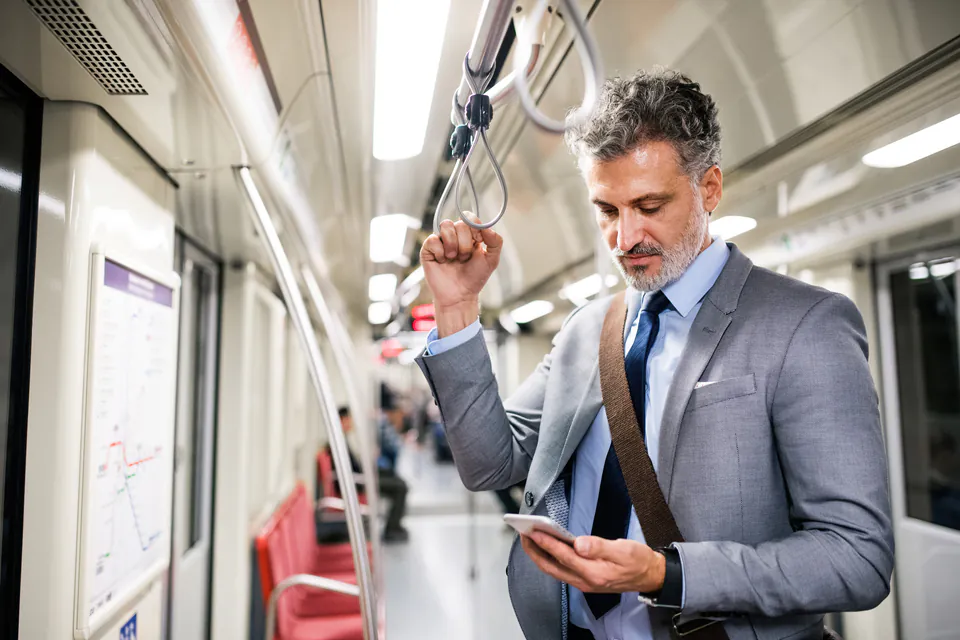 Interior of modern metro train with passenger checking phone