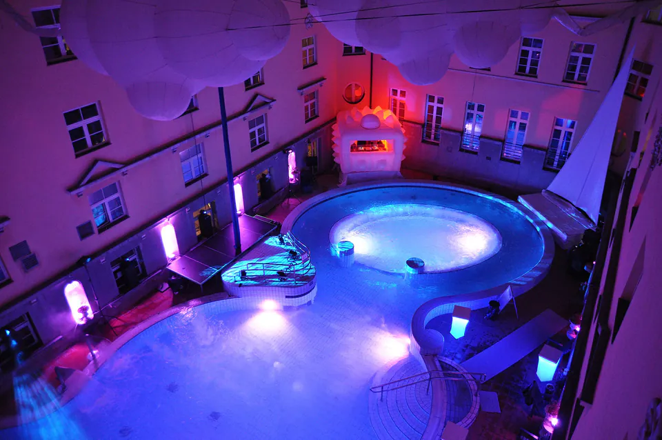 Illuminated adventure pool with whirlpool and lazy river lit by purple and blue lights at night