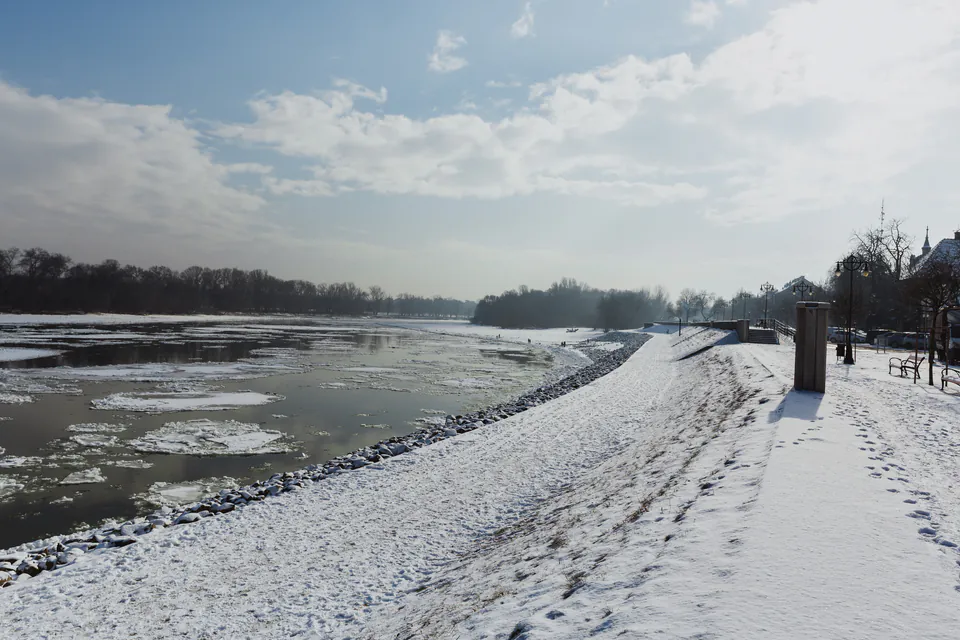Snow-covered Danube riverbank with ice floes floating on water during winter in Szentendre